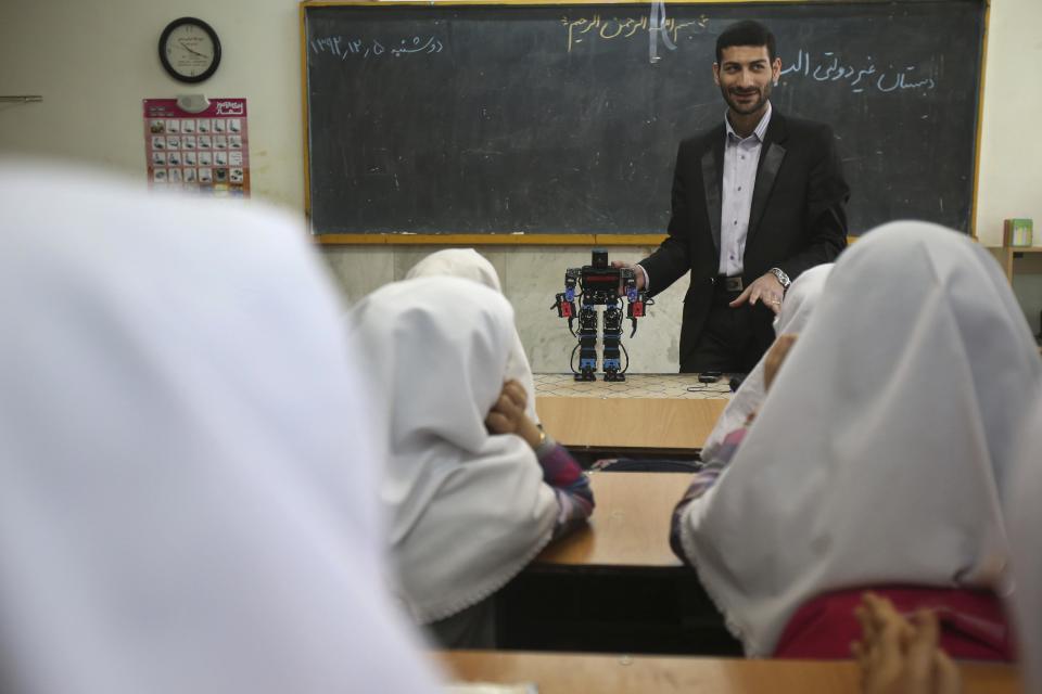 In this picture taken on Monday, Feb. 24, 2014, Iranian schoolteacher Akbar Rezaie presents his humanoid praying robot, Veldan, for Alborz elementary school girls in the city of Varamin some 21 miles (35 kilometers) south of the capital Tehran, Iran. Rezaei who has built a robot to show to children how to execute daily prayers, has innovated an amusing way of encouraging young children to say their daily prayers by using the science of robotics. Out of personal interest and unrelated to his field of study, Akbar Rezaei attended private robotics classes and acquired the skill of assembling and developing customized humanoid robots. He built the robot at home with basic tools and gave it the designation “Veldan”, a term mentioned in Quran meaning: “Youth of Heaven”. By applying some mechanical modifications such as adding up two extra engines Akbar Rezaei managed to let the robot perform praying movements, such as prostration, more easily. (AP Photo/Vahid Salemi)