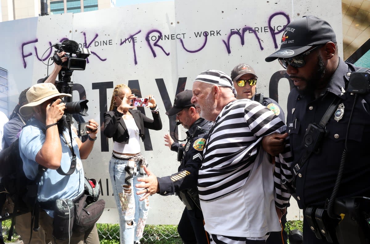 Protester Dominic Santana is detained by Miami Police officers after attempting to rush former President Donald Trump's motorcade (Getty Images)