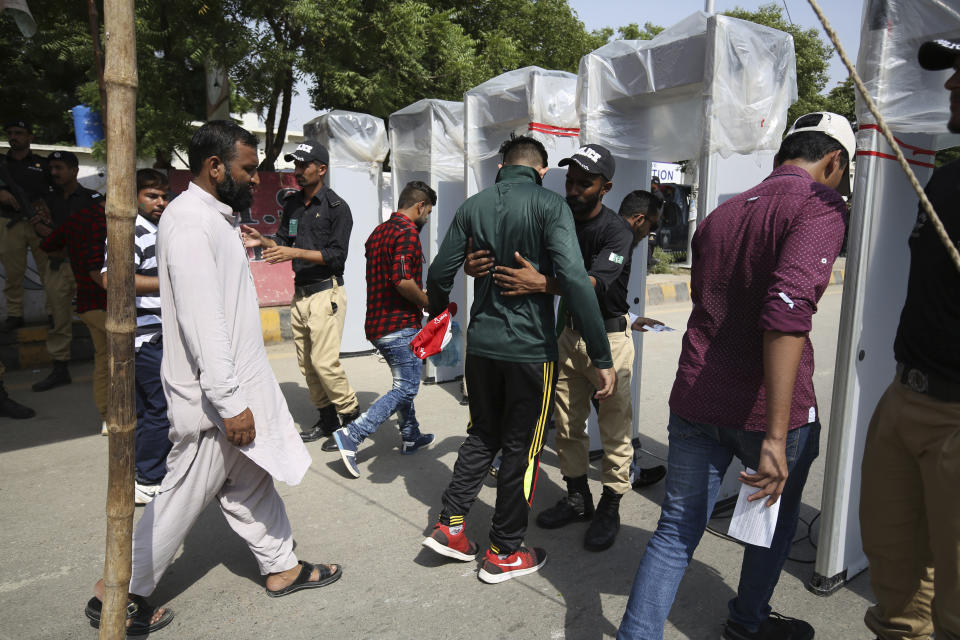 Pakistani police officers search spectators outside the National stadium in Karachi, Pakistan, Monday, Sept. 30, 2019. Karachi's 10-year long wait to host a one-day international finally ended on Monday as Pakistan won the toss and elected to bat against Sri Lanka in the second ODI. (AP Photo/Fareed Khan)