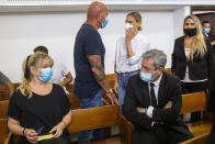 Israeli top model Bar Refaeli, center, wearing a face mask arrives to a court along with her mother, Zipi, left, her father, Raffi, center, and lawyers, in Tel Aviv, Israel, Monday, July 20, 2020. Refaeli signed a plea bargain agreement with authorities to settle a long-standing tax evasion case against her and her family. The deal will require Refaeli to serve nine months of community service while her mother, Zipi, will be sent to prison for 16 months. The two are also ordered to pay a $1.5 million fine on top of millions of back taxes owed to the state. (AP Photo/Oded Balilty, Pool)