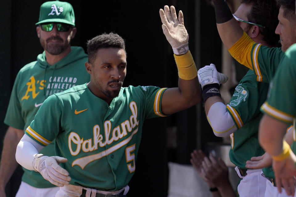 Oakland Athletics' Tony Kemp (5) is congratulated by teammates after scoring against the San Francisco Giants during the sixth inning of a baseball game in Oakland, Calif., Sunday, Aug. 22, 2021. (AP Photo/Jeff Chiu)