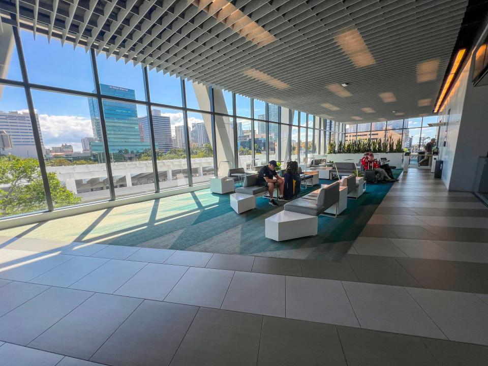 The premium lounge at the Fort Lauderdale Brightline station is shown. Low couches, tables and floor-to-ceiling windows occupy the space.