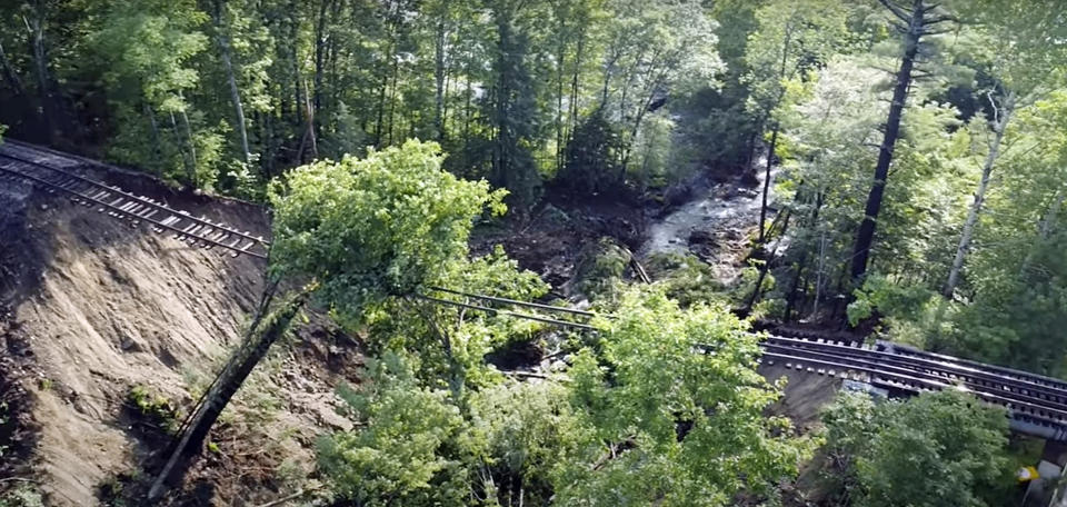 This July 11, 2023 image taken from video and provided by Pat Moore shows a rail bridge over Mountain Road that washed out by flash flooding in Ludlow, Vt. (Pat Moore via AP)
