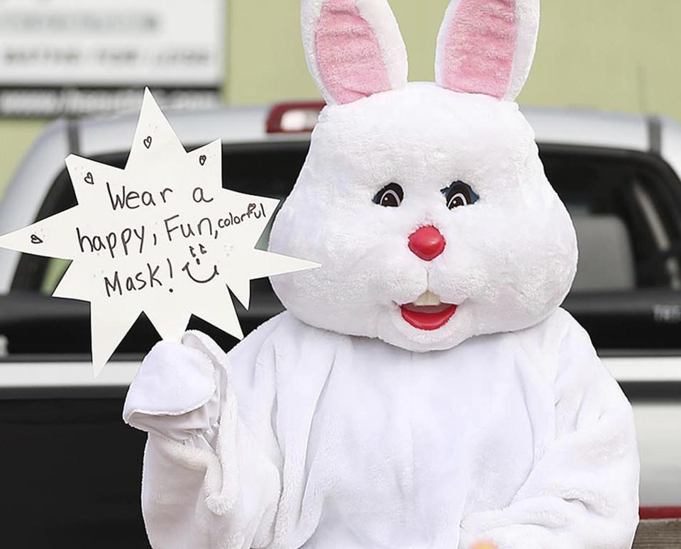 The Easter Bunny encourages people to wear a mask during an Easter parade in Orlando, Fla., on Saturday, April 11, 2020. The parade, conducted with "social distancing" to prevent the spread of coronavirus. (Stephen M. Dowell/Orlando Sentinel via AP)