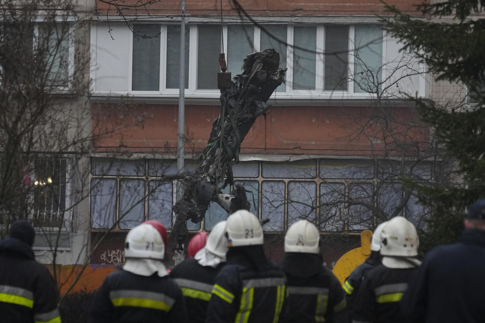 A crane lifts a part of helicopter at the scene where a helicopter crashed on civil infrastructure in Brovary, in the outskirts of Kyiv, Ukraine, Wednesday, Jan. 18, 2023. The chief of Ukraine's National Police says a helicopter crash in a Kyiv suburb has killed 16 people, including Ukraine's interior minister and two children. He said nine of those killed were aboard the emergency services helicopter. (AP Photo/Efrem Lukatsky)