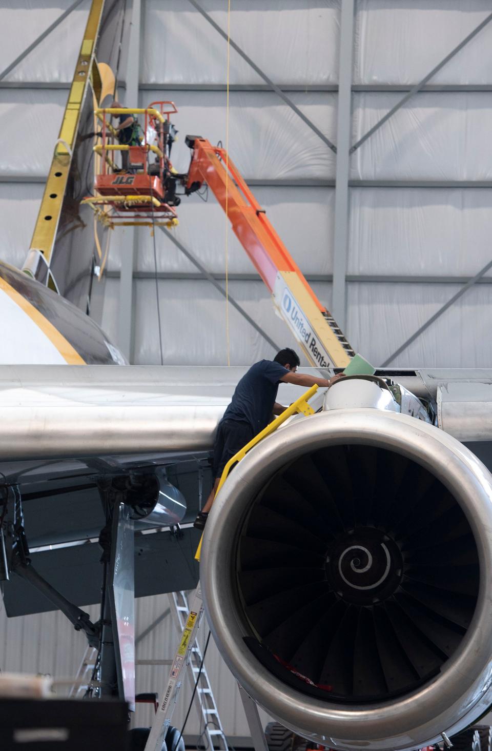 Aviation maintenance workers service a Boeing 757 operated by UPS on Oct. 14 at ST Engineering's facility at the Pensacola International Airport. ST Engineering has hired just over 200 employees, reaching the halfway mark for the 400 new jobs that its first hangar promised to deliver.