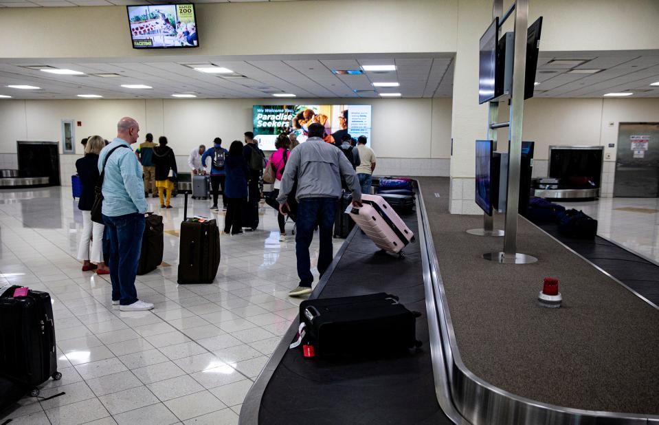 Travelers pick up luggage at baggage claim at Southwest Florida International Airport on Monday, Feb. 27, 2023.  