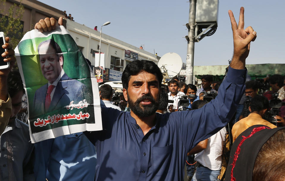 A supporter of former Pakistani Prime Minister Nawaz Sharif holds his picture and makes a victory sign after a court ruling, outside the Islamabad High Court in Islamabad, Pakistan, Wednesday, Sept. 19, 2018. The Pakistani court suspended the prison sentences of Sharif, his daughter and son-in-law on Wednesday and set them free on bail pending their appeal hearings. The court made the decision on the corruption case handed down to the Sharifs by an anti-graft tribunal earlier this year. (AP Photo/Anjum Naveed)