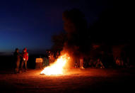 Migrants, part of a caravan of thousands traveling from Central America en route to the United States, warm themselves over a bonfire at a makeshift camp at a gas station where the migrants wait for buses in Navojoa, Mexico November 16, 2018. REUTERS/Kim Kyung-Hoon