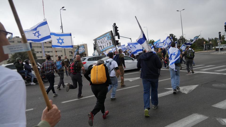 Military reservists run toward the site of a protest against judicial reforms in Israel on April 20, 2023.