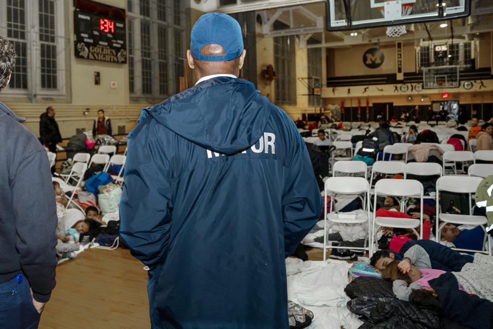 In this photo provided by the Office of the Mayor New York, New York Mayor Eric Adams visits with asylum seekers taking shelter at James Madison High School, in the Brooklyn borough of New York, Tuesday, Jan. 9, 2024.