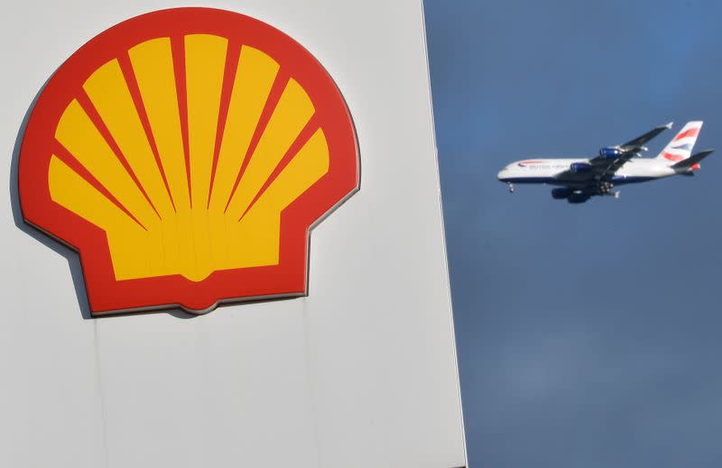 A passenger plane flies behind a Shell logo at a petrol station in west London
