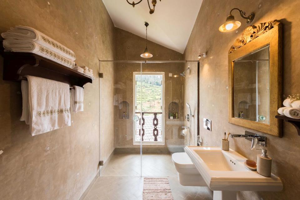 The earthy palette of this ensuite bathroom highlights the rolling, green view.