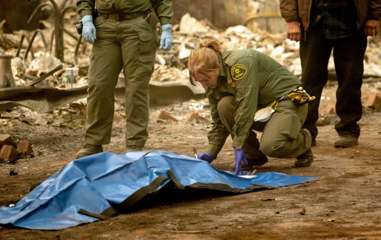 A Fresno County Sheriff's officer tends to a body recovered at a burned residence in Paradise, California