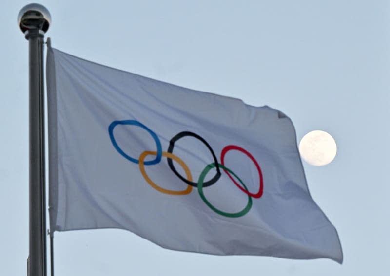 The moon can be seen behind the flag with the Olympic rings. Peter Kneffel/dpa