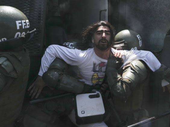 Police detain a protester in Santiago (Esteban Felix/AP)