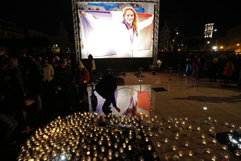 People lay candles near a picture of swimming gold medallist Camille Muffat on March 10, 2015 in her hometown of Nice, France