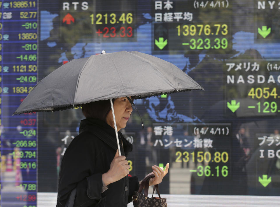 A woman walks by an electronic stock board of a securities firm in Tokyo, Friday, April 11, 2014. Tokyo's Nikkei 225 stock average fell more than 400 points at one point in morning trading. (AP Photo/Koji Sasahara)