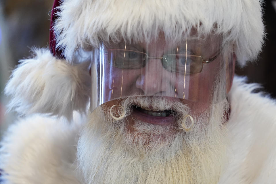 Santa Claus wears a face shield while visiting with children at Bass Pro Shop in Rancho Cucamonga, Calif., on Dec. 4, 2020. In this socially distant holiday season, Santa Claus is still coming to towns (and shopping malls) across America but with a few 2020 rules in effect. (AP Photo/Ashley Landis)