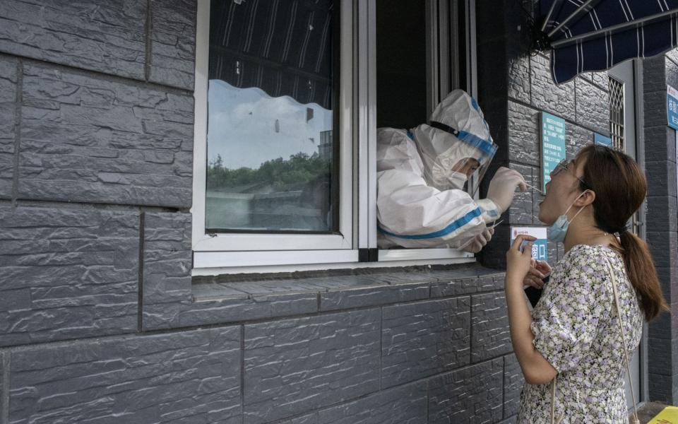 A healthcare worker takes a swab sample at a Covid-19 testing facility in Beijing, as China attempts to contain its broadest outbreak of Covid since it crushed the virus that first emerged in Wuhan in late 2019 - Gilles Sabrie/Bloomberg