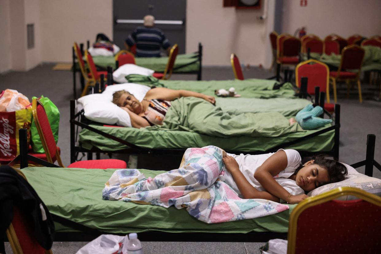 People who were evacuated from Nea Aghialos during a wildfire rest inside a municipal building used as shelter in the city of Volos (REUTERS)