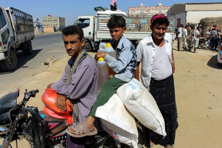 A man and child ride on a motorcycle loaded with sacks of wheat and cooking oil containers distributed as food aid by a local charity at a camp for the displaced, in the northern Yemeni province of Hajjah on December 23, 2017