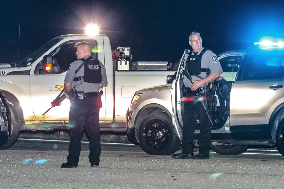 Police officers stand at the scene following a police chase Monday, April 12, 2021, in Carroll County, Ga. Georgia authorities say multiple officers were injured when the passenger of a car shot them during a police chase that ended with one suspect killed and the other arrested. (John Spink/Atlanta Journal-Constitution via AP)