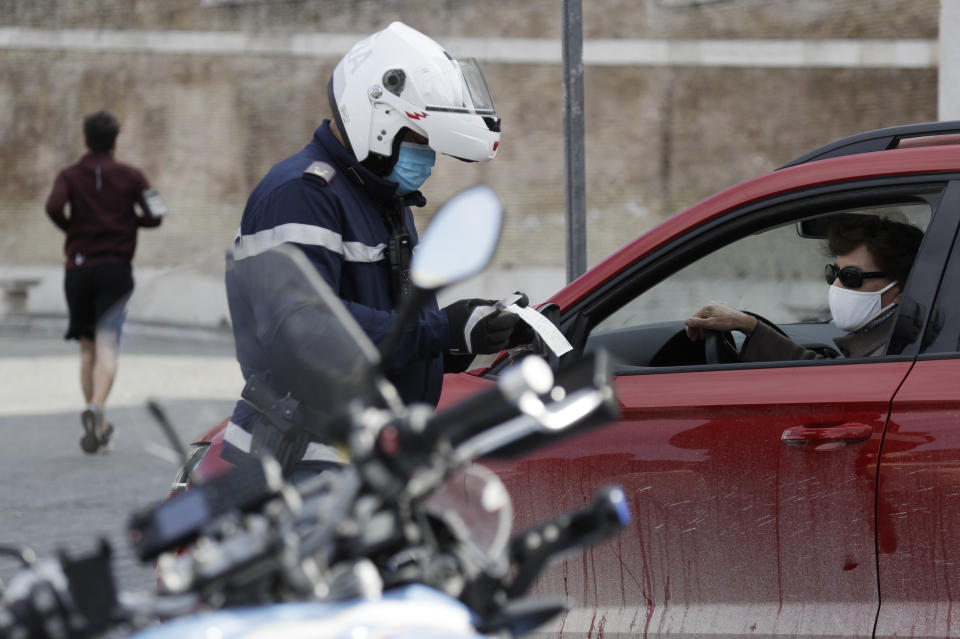 A Police officer check's a documents at a road block in Rome's central Piazza del Popolo, Saturday, April 3, 2021. Italy went into lockdown on Easter weekend in its effort to battle then Covid-19 pandemic. (AP Photo/Gregorio Borgia)