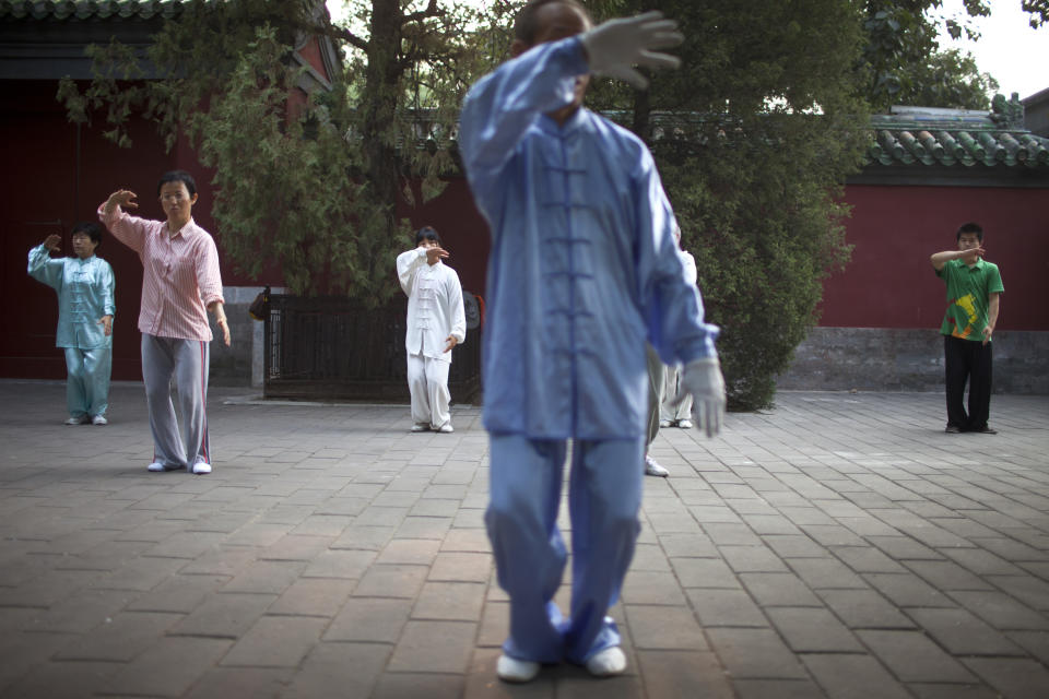 In this Tuesday, July 17, 2012 photo, people practice tai chi during their morning exercise at Ritan Park in Beijing, China. Some of the bigger parks in Beijing charge admission, but not Ritan Park, the historic garden where emperors once made offerings to the sun in an ancient circular wall-enclosed altar. (AP Photo/Alexander F. Yuan)