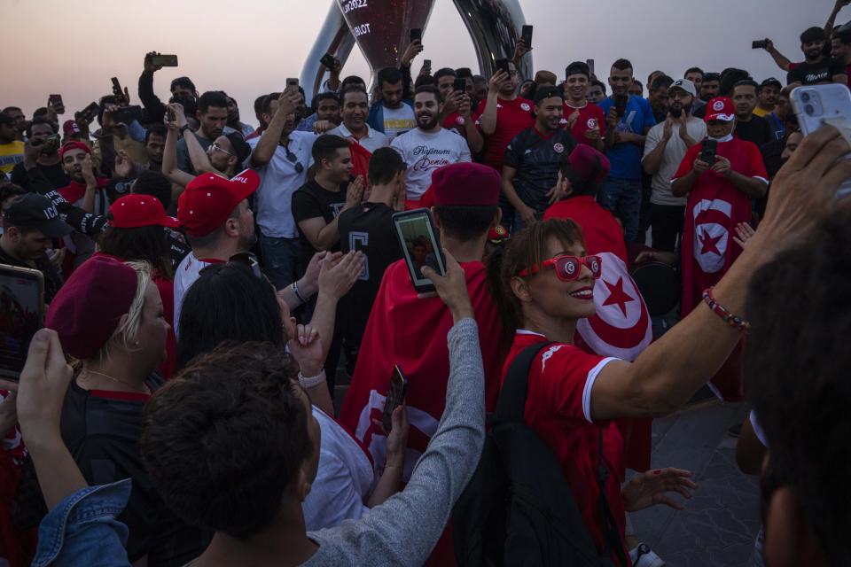 Tunisian football fans celebrate their team, who will be competing in the World Cup finals for a sixth time, in front of the official FIFA World Cup Countdown Clock on Doha's corniche, 30 days ahead until the start of the World Cup, in Qatar, Friday, Oct. 21, 2022. Around 1.2 million visitors are expected in Qatar for the first World Cup to be played in the Middle East. (AP Photo/Nariman El-Mofty)