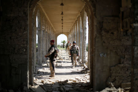 Miembros de las fuerzas de seguridad iraquíes hacen guardia mientras el violinista Ameen Mukdad da un pequeño concierto en el santuario de Nabi Yunus en el este de Mosul, Irak, 19 de abril de 2017. En medio de las ruinas bombardeadas de un antiguo lugar venerado por musulmanes y cristianos en Mosul, Mukdad realizó el miércoles un pequeño concierto en la ciudad de la que huyó obligado por milicianos de Estado Islámico. REUTERS/ Muhammad Hamed