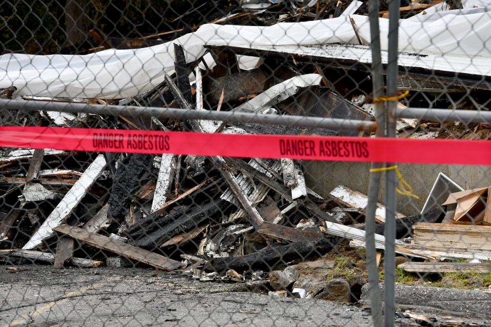 Asbestos warnings hang from the fence around the First Congregational Church's partially-covered wreckage Monday.