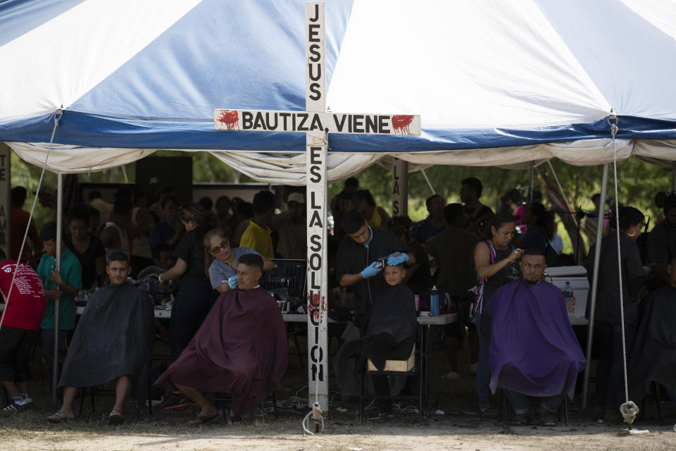 In this Oct. 11, 2019 photo, migrants get free haircuts by volunteers at a migrant camp near a legal port of entry bridge in Matamoros, Mexico. Tamaulipas became a bloody emblem of the problem of violence against migrants in 2010 when 72 migrants were found slain at a ranch in San Fernando, and a year later when the bodies of 193 migrants were found in the same area in clandestine mass graves, apparently murdered by a cartel to damage a rival’s people-smuggling business. (AP Photo/Fernando Llano)