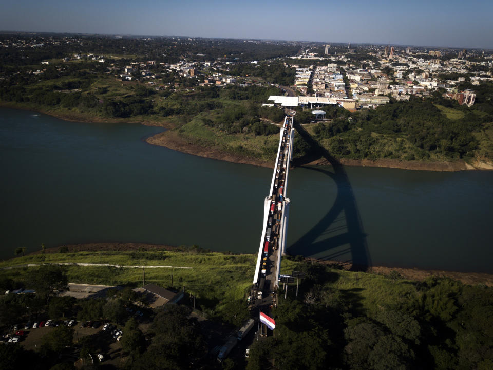 Trucks wait in line on Friendship Bridge over the Parana River, the natural border between Foz do Iguazu, Brazil, top, and Ciudad del Este, Paraguay, during the COVID-19 quarantine, Tuesday, June 23, 2020. There are complaints of delays from many of the 15,000 Paraguayans still waiting to reenter Paraguay, outside the country in neighboring nations like Brazil and Argentina. (AP Photo/Jorge Saenz)