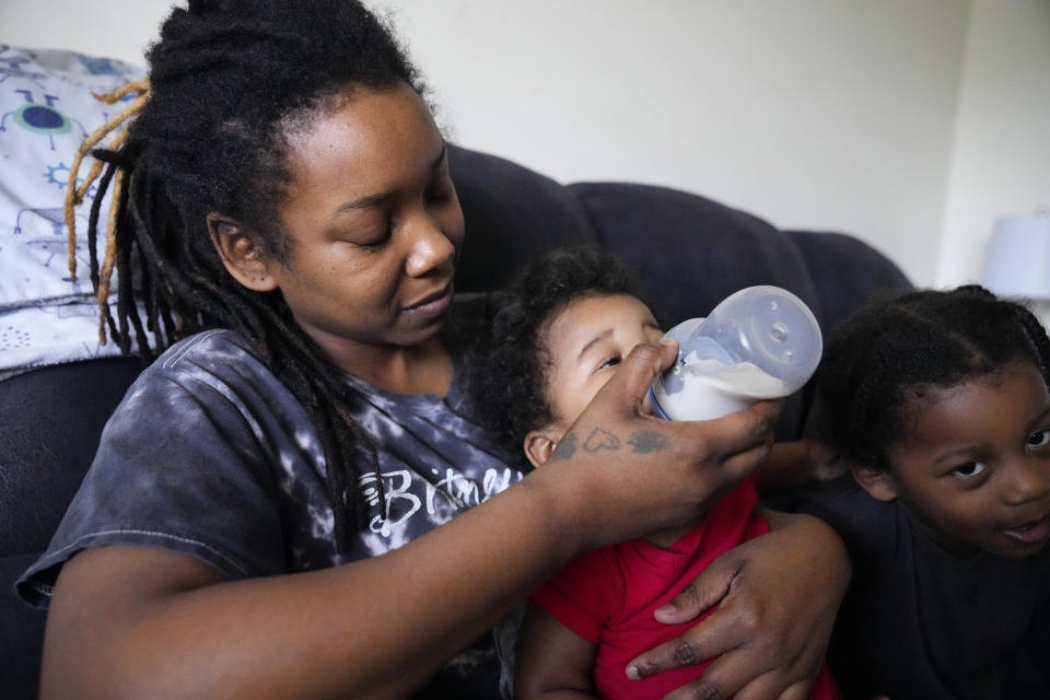 Ashley Yancey feeds her 11 month-old daughter Olivia as two-year old Oliver Tolvert looks on at right Thursday, Dec. 14, 2023, in Douglasville, Ga. Yancey, who doesn't own a car, recently tried to find formula for her daughter at a Target about 30 miles from her home in and was stunned the location didn’t accept WIC. Often, her nearest WIC vendor is out of the product. (AP Photo/John Bazemore)