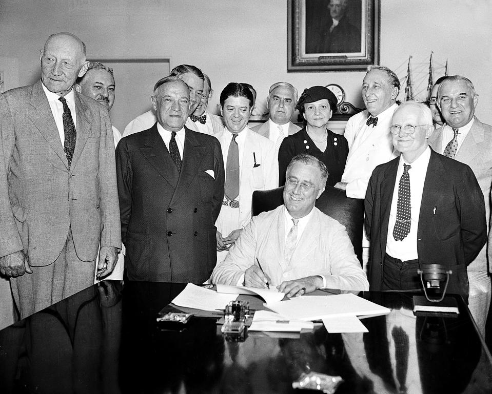 FILE - In this Aug. 14, 1935, file photo President Franklin Roosevelt signs the Social Security Bill in Washington. In 1935 Americans struggle to pay for medical care amid the Great Depression. Roosevelt favors creating national health insurance, but decides to push for Social Security first. He never gets the health program passed. But his Social Security bill will provide old age pensions and unemployment insurance. From left are: Chairman Doughton of the House Ways and Means Committee; Sen. Wagner, D-N.Y, co-author of the bill, Secretary Perkins, Chairman Harrison of the Senate Finance Committee, Rep. Lewis, D-Md., co-author of the measure. (AP Photo/File)