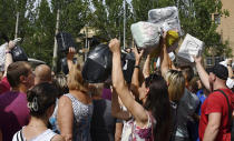 Local residents, many of whom fled the war, gather to hand out donated items such as medicines, clothes, and personal belongings to their relatives on the territories occupied by Russia, in Zaporizhzhia, Ukraine, Sunday, Aug. 14, 2022. Volunteers transport these items across the frontline and distribute them to addresses at their own risk. (AP Photo/Andriy Andriyenko)