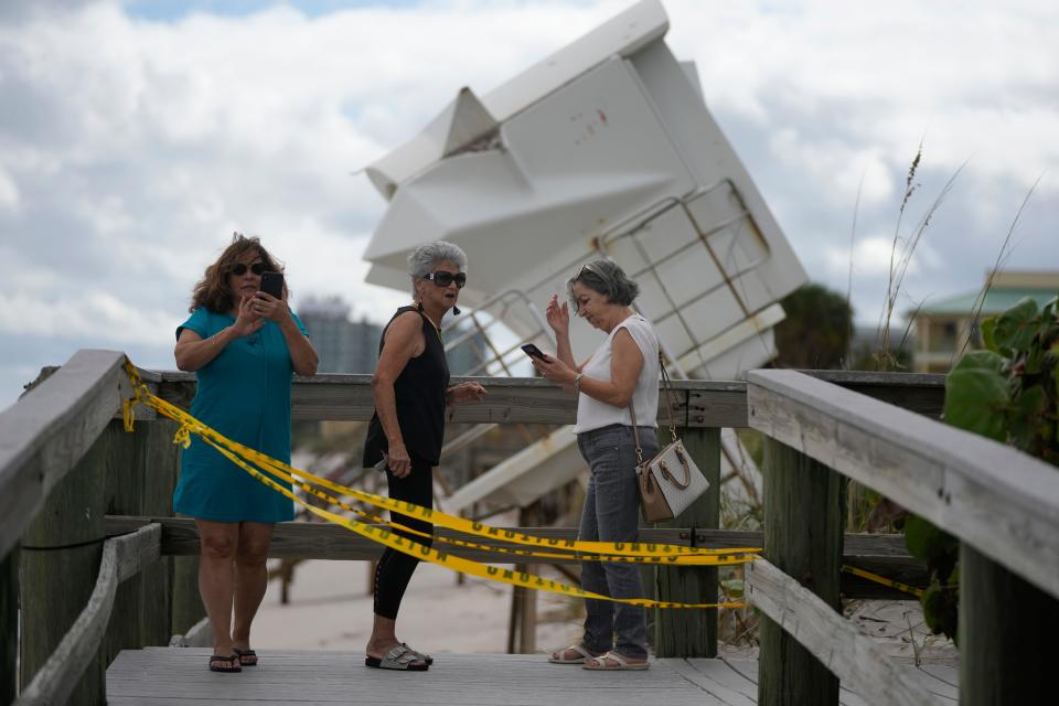 People visit the beach to investigate storm damage, including a lifeguard station that was displaced onto a dune, following the passage of Hurricane Nicole, Thursday, Nov. 10, 2022, in Vero Beach, Fla. (AP Photo/Rebecca Blackwell)