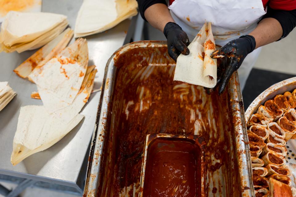 Nilfa Farfan, an employee at Food City Supermarket in El Paso, Texas, folds and wraps the corn tusk after adding red chile covered pork to the center of the masa for the tamales on Tuesday, Dec. 19, 2023.