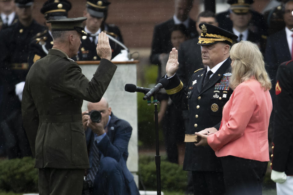 Chairman of the Joint Chiefs of Staff Gen. Mark Milley, center, with his wife Hollyanne Milley, participates in a ceremonial swearing in by former chairman Gen. Joseph Dunford, left, at Joint Base Myer-Henderson Hall, Va., Monday, Sept. 30, 2019. (AP Photo/Manuel Balce Ceneta)