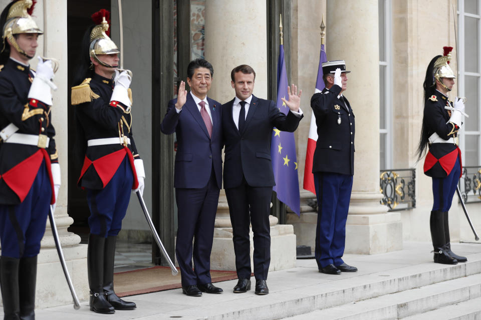 French President Emmanuel Macron, center right, and Japan's Prime Minister Shinzo Abe wave before their talks at the Elysee Palace, Tuesday, April 23, 2019 in Paris. (AP Photo/Thibault Camus)