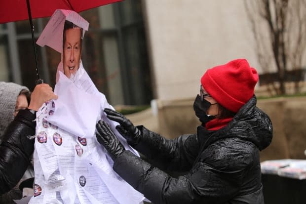 A person touches the notices to ensure they remain in place during the protest on a grey and rainy Sunday afternoon.