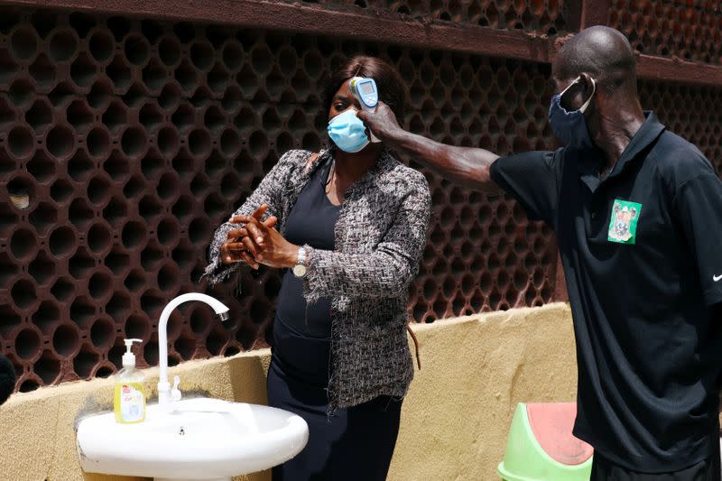 A security staff uses a thermal scanner to check a temperature of a member of the contact-tracing team, at the Primary Healthcare Centre in Lagos