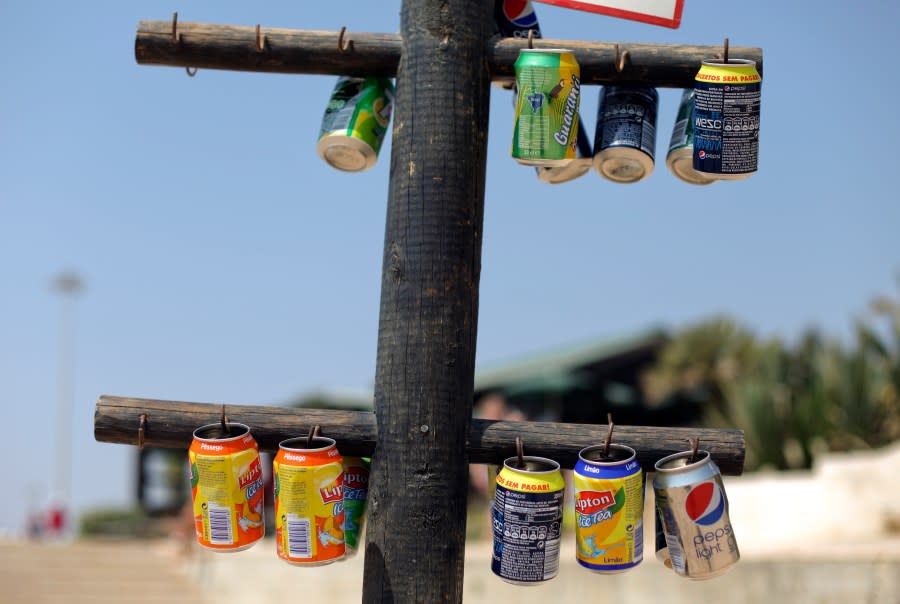 FILE – Empty soft drink cans hung in a post to be used as ashtrays at Carcavelos beach in Cascais, near Lisbon, Wednesday, Aug. 28, 2013. Global supermarket chain Carrefour will stop selling PepsiCo products in its stores in France, Belgium, Spain and Italy over price increases for popular items like Lay’s potato chips, Quaker Oats, Lipton tea and its namesake soda. (AP Photo/Francisco Seco, File)