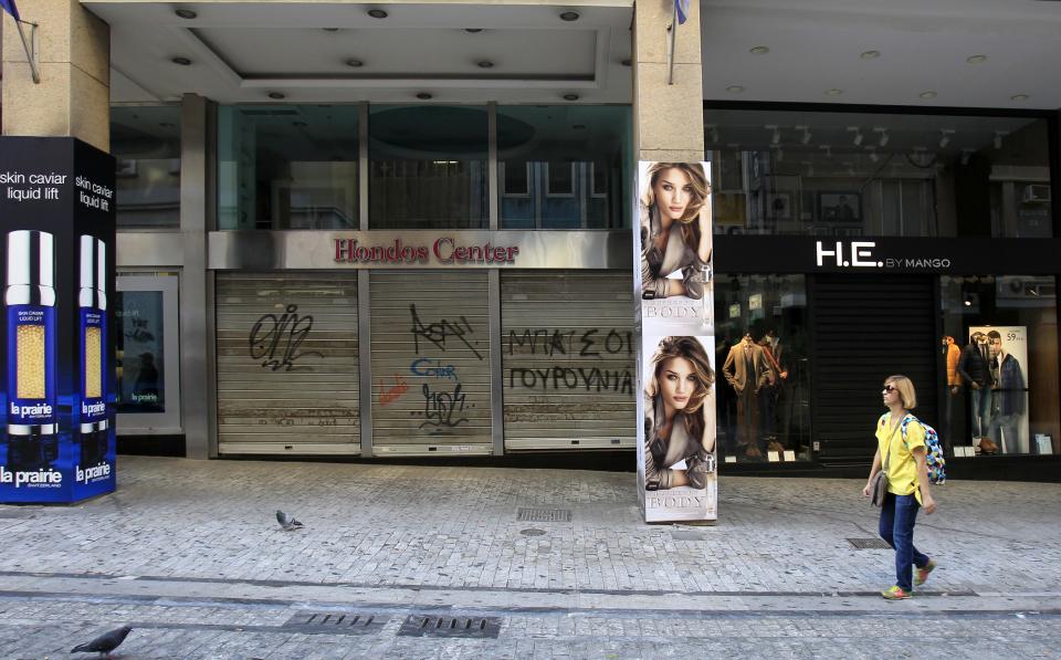 A woman walks past closed shops at the main commercial Athens' Ermou street on Tuesday Nov. 6, 2012. Greece's unions are holding their third general strike in six weeks to press dissenters in the country's troubled coalition government not to back a major new austerity program that will doom Greeks to further hardship in a sixth year of recession. (AP Photo/Nikolas Giakoumidis)