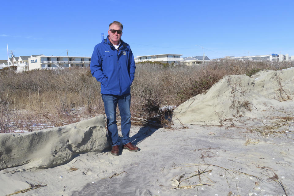 Mayor Patrick Rosenello stands next to a destroyed section of sand dune in North Wildwood N.J. on Jan. 22, 2024. A recent winter storm punched a hole through what is left of the city's eroded dune system, leaving it more vulnerable than ever to destructive flooding as the city and state fight in court over how best to protect the popular beach resort. (AP Photo/Wayne Parry)