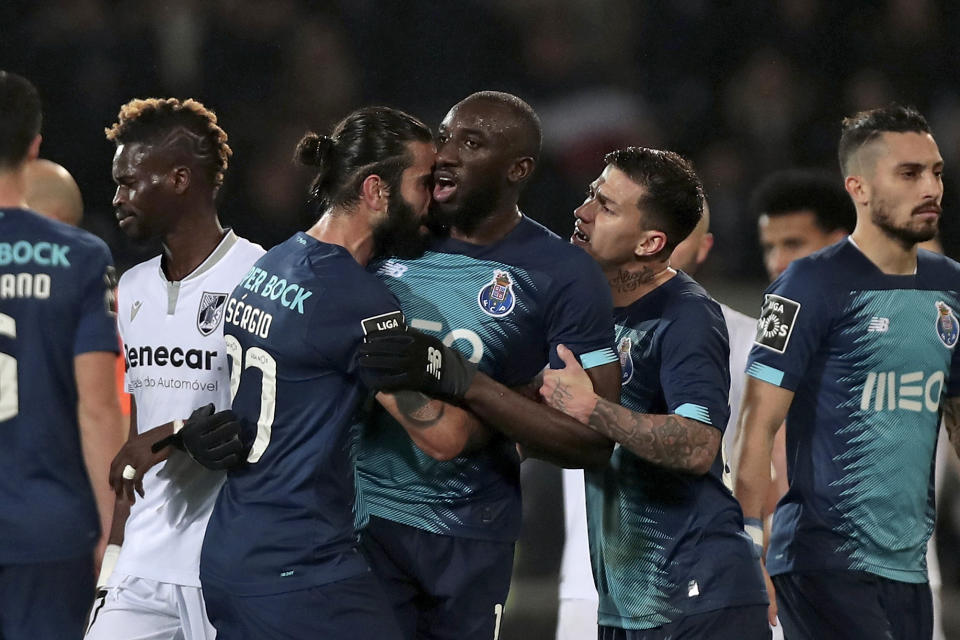 FILE - Porto's Sergio Oliveira, center left, and Otavio, center right, talk with teammate Moussa Marega, center, as he tries leaves the pitch after hearing racist chants during a Portuguese league soccer match between Vitoria SC and FC Porto in Guimaraes, Portugal on Sunday, Feb. 16, 2020. Porto forward Moussa Marega had been racially abused by Vitoria fans who threw seats at him after he scored and pointed to his skin. When Marega, who was born in France but plays for Mali's national team, carried one of the seats above his head in defiance the referee gave him a yellow card. He then tried to walk off as teammates physically kept him on the field. (AP Photo)