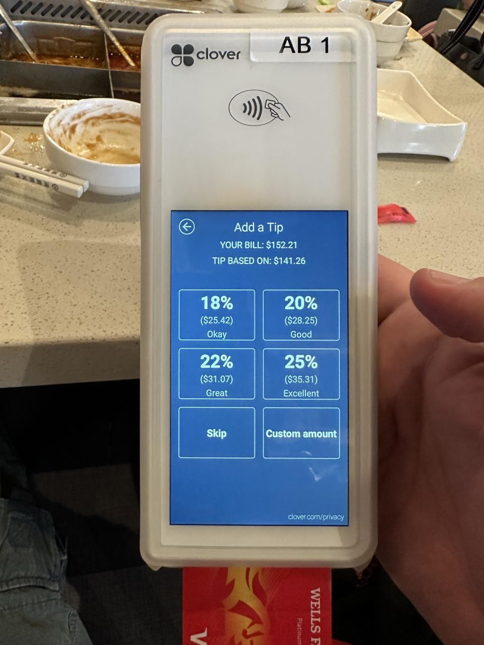 A hand holds a Clover payment device showing tip options for a $152.21 bill: 18% ($28.42), 20% ($31.61), 22% ($34.31), and 25% ($35.31). There are skip and custom amount buttons