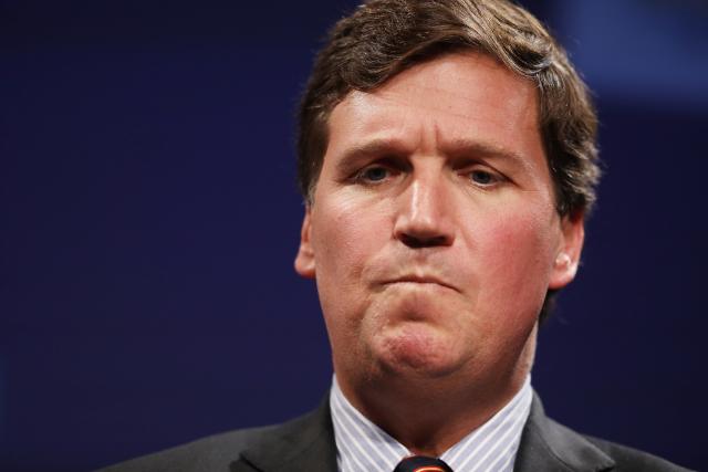 A headshot of Tucker Carlson looking towards the right with a contemplative look on his face.
