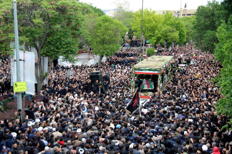 In this photo provided by Fars News Agency, mourners gather around a truck carrying coffins of Iranian President Ebrahim Raisi and his companions who were killed in a helicopter crash (AP)